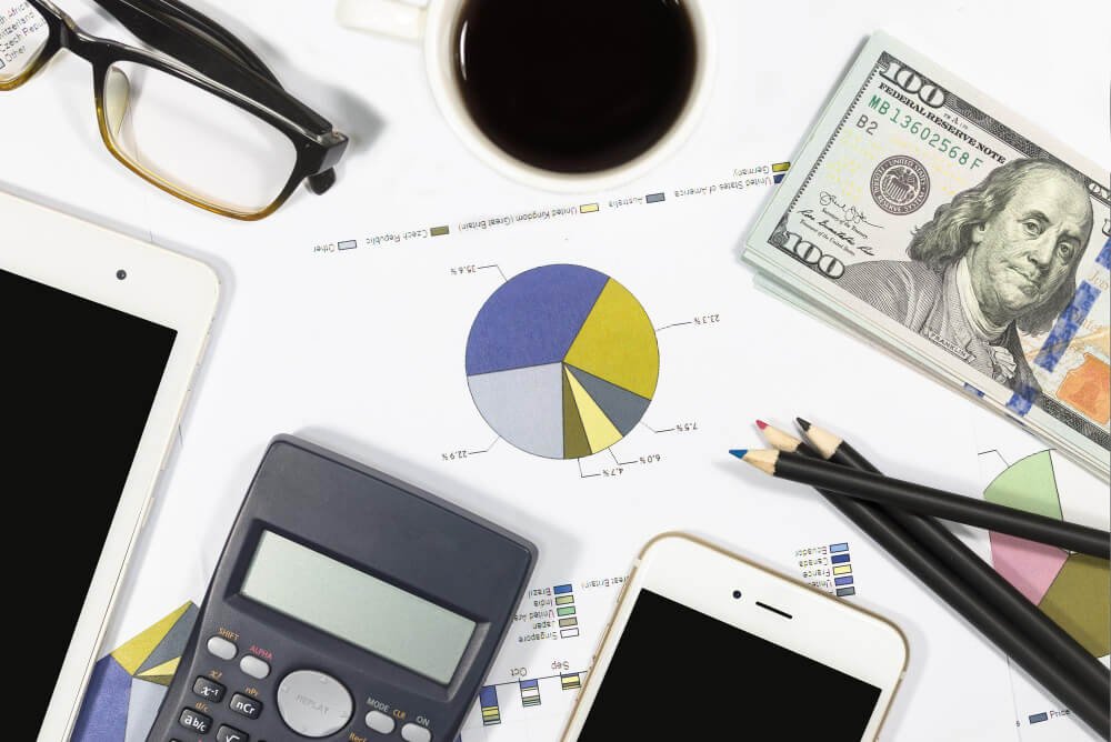 Caneta de calculadora de notas de dólar óculos de café tablet celular e gráficos de negócios estão na mesa